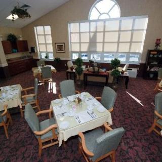 A well-lit dining room with neatly arranged tables and chairs, featuring large windows that allow ample natural light.