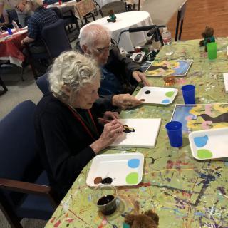 Elderly individuals participating in a painting activity.