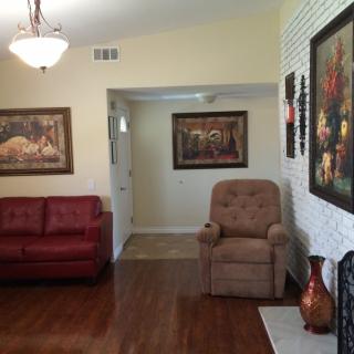 A cozy living room featuring a red sofa, a brown armchair, and decorative paintings on the walls.