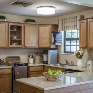 A modern kitchen with wooden cabinets, a countertop with a fruit basket, and various appliances.