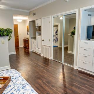 A modern bedroom with hardwood flooring and mirrored closet doors.