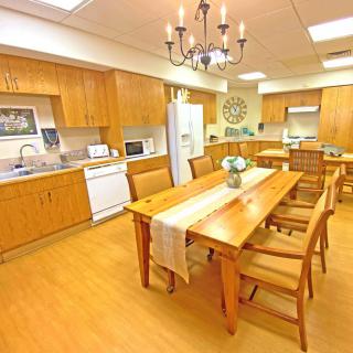 A spacious kitchen with wooden cabinetry and a large dining table under a chandelier.