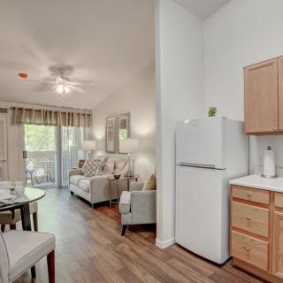 Spacious apartment with a cozy living room and adjoining kitchen area, featuring modern furnishings and wood flooring.