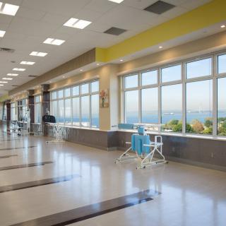 A bright, modern hospital corridor with large windows and seating areas.
