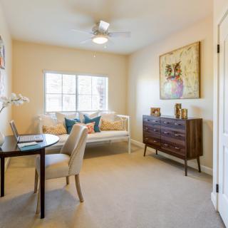 A cozy home office space with a desk, chair, sofa, and decorative artwork.