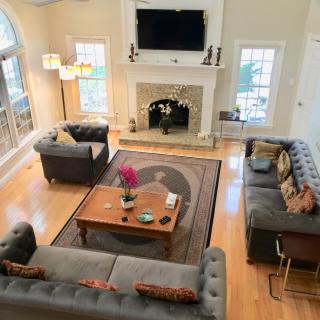 A spacious living room with contemporary decor, featuring a central coffee table, stylish sofas, a fireplace, and a wall-mounted television.