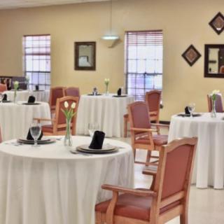 A neatly arranged dining room with round tables and wooden chairs.