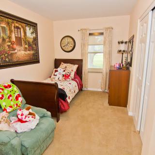 A cozy child's bedroom featuring a twin bed, a plush chair, and charming wall decor.