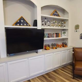 A living room with built-in shelves displaying decorative items, a television, and flag display cases.
