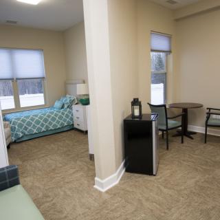 A cozy bedroom with a bed, table, and chairs arranged neatly in a well-lit room.