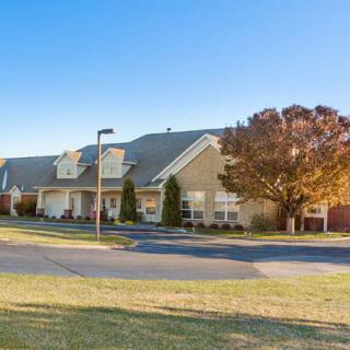 A suburban residential building with a well-maintained lawn and trees under a clear blue sky.