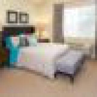 A cozy, well-decorated bedroom with a neatly made bed and natural lighting.