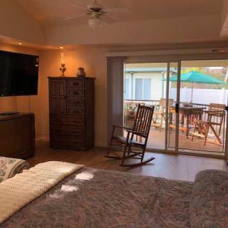 A cozy bedroom with a rocking chair, television, and a view of the patio through sliding glass doors.