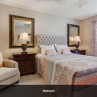 A well-decorated bedroom with a bed, mirrors, and lamps.
