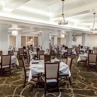 A spacious and elegantly decorated dining room with multiple tables and chairs arranged neatly.