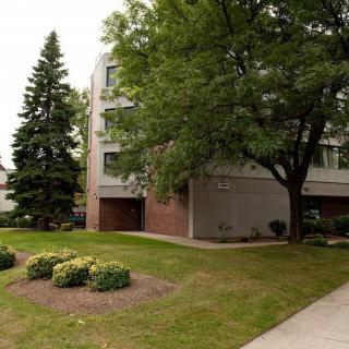 A residential building surrounded by trees and well-maintained landscaping.