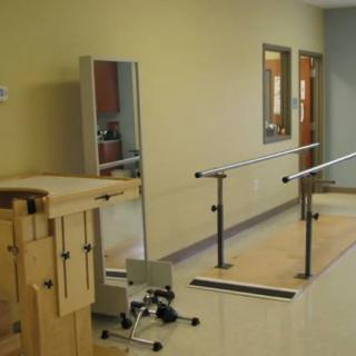 A physical therapy room equipped with parallel bars and exercise tools for patient rehabilitation.