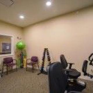 A small exercise room with various fitness equipment and chairs.
