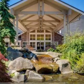 A scenic view of a building entrance with a landscaped garden and water feature.