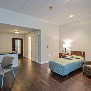 A cozy studio apartment featuring a bed, seating area, and modern finishes.