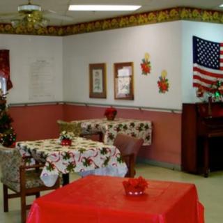 A cozy indoor setting with tables decorated with floral tablecloths, an American flag on the wall, and a piano in the corner.