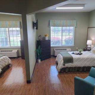 A cozy bedroom featuring two beds and large windows with natural light.