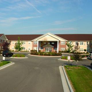 A hotel building with a driveway and landscaped entrance on a clear day.