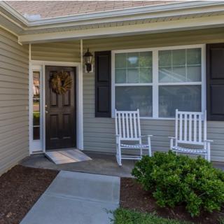 A cozy front porch with two white rocking chairs beside the entrance.