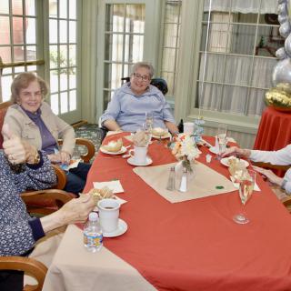 A group of seniors enjoying a meal together, seated around a decorated table indoors.
