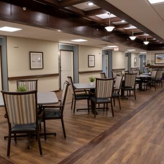A well-appointed dining area with wooden floors, tables, and chairs, featuring elegant lighting and decor.