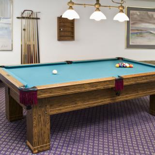 A billiards table set up with cue sticks in a game room.