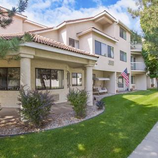 A residential apartment complex with a well-maintained lawn and an American flag displayed.