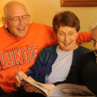 A group of elderly people enjoying a book together on a cozy couch.
