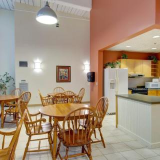 A cozy dining area featuring wooden tables and chairs adjacent to a small kitchen space.