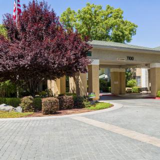 A welcoming hotel entrance with well-maintained landscaping and a paved driveway.
