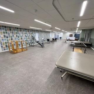 A spacious and modern physical therapy room equipped with treatment tables and exercise equipment.