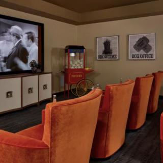 A cozy home theater with plush orange seating and a large movie screen, complete with a classic popcorn machine.