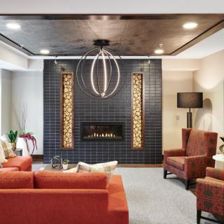 A modern living room featuring a stylish fireplace, contemporary seating, and a unique chandelier.