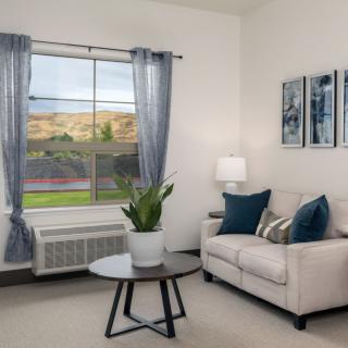 A cozy living room with a sofa, coffee table, and decorative elements including a plant and artwork.