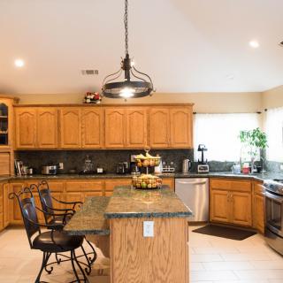 A spacious kitchen featuring wooden cabinets, an island with bar stools, and modern lighting.