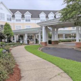 A well-maintained building with a pathway leading to the entrance, surrounded by greenery.