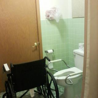 A wheelchair positioned next to a bathroom toilet, highlighting accessibility features.