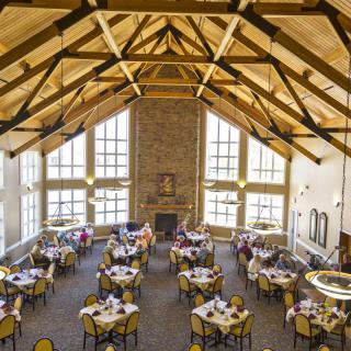 A beautifully arranged banquet hall with decorated tables and high ceilings, ready for an event.