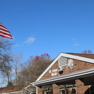 A clear blue sky with an American flag waving over a brick building.