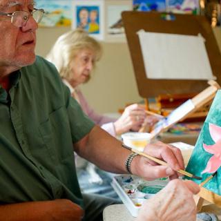 Seniors engaged in a painting class, focusing on their artwork.