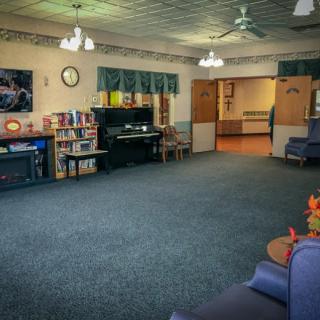 A spacious lounge area with a piano, bookshelf, and comfortable seating.