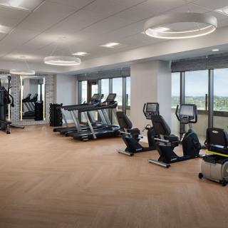 A modern gym with various fitness equipment and large windows.