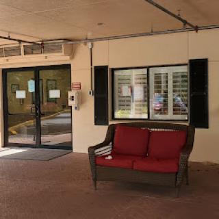 A cozy seating area outside an entrance, featuring a red couch and large windows.