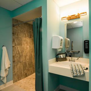 A modern bathroom featuring turquoise walls, a walk-in shower, and a sleek sink area.