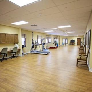 A spacious gym with exercise equipment, including treadmills, in a well-lit interior featuring wooden floors.